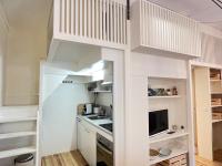 a small kitchen with white cabinets and a loft bed at Joli studio + mezzanine 2-3 Pers in Cauterets