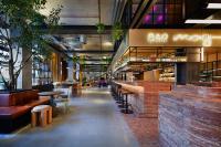 Un bar con bancos y mesas en un edificio. en Moxy Sydney Airport, en Sídney