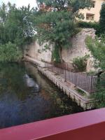 a river next to a stone wall and trees at APPARTEMENT ATYPIQUE LE THOR in Le Thor