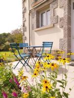 two chairs and flowers in front of a building at Gîte-appartement sur la Côte d&#39;Emeraude in Beaussais sur Mer