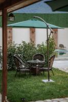 a table and chairs with an umbrella in the grass at Hotel Piano Kvareli in Kvareli