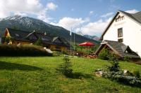 a building with a grass field in front of a house at Reitmayer in Smokovce