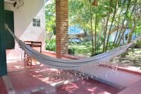 a hammock outside of a house with trees at Pousada São Francisco in Cumuruxatiba