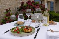 Una mesa con un plato de comida y copas de vino. en Le Poutic gîte et maison d'hôtes, en Créon-dʼArmagnac