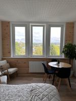 a bedroom with three windows and a table and chairs at Le Petit Port in Sedan