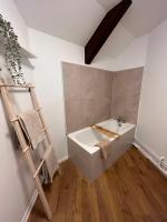 a bathroom with a white bath tub and a wooden floor at Le Petit Port in Sedan