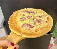 een persoon die een pizza vasthoudt op een houten spatel bij Fancy Hostel and Bar in Ha Long