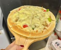 een persoon die een pizza vasthoudt op een houten spatel bij Fancy Hostel and Bar in Ha Long