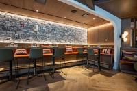 a bar with chairs and a stone wall at Everwild Canmore Hotel in Canmore