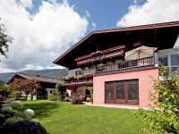 a pink house with a balcony and a yard at Apartment in Bramberg am Wildkogel with balcony in Bramberg am Wildkogel