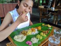 a woman sitting at a table with a plate of food at Rainforest Resort in Athirappilly