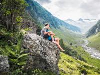 a person sitting on a rock overlooking a valley at Apartment in Bramberg am Wildkogel with balcony in Bramberg am Wildkogel
