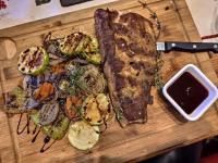 a cutting board with a steak and vegetables on it at Spider House Aparthotel in Pamporovo