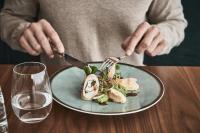 uma pessoa a comer um prato de comida com um garfo e uma faca em Falkensteiner Balance Resort Stegersbach - Adults only em Stegersbach