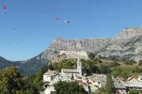a bird flying over a town in front of a mountain at Chez Pierrette et Eugène Prix nuitée&#47;10 personne in Le Lautaret