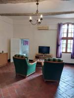 a living room with two green chairs and a television at La Quiétude in Cotignac