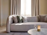 a living room with a grey couch with a wine glass at The Playford Adelaide - MGallery in Adelaide