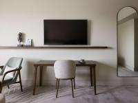 a table with a chair and a television on a wall at The Playford Adelaide - MGallery in Adelaide