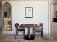 a dining room table with two chairs and a mirror at The Playford Adelaide - MGallery in Adelaide