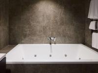 a bath tub with a faucet in a bathroom at The Playford Adelaide - MGallery in Adelaide