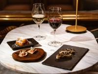 a table topped with two glasses of wine and desserts at The Playford Adelaide - MGallery in Adelaide