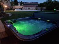 a hot tub with lights in a backyard at night at Au pool house de la Faye avec jacuzzi in Saint-Romain-Lachalm