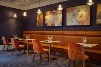 um restaurante com duas mesas e cadeiras e quadros na parede em DoubleTree by Hilton London Elstree em Borehamwood