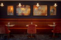 um restaurante com três mesas e cadeiras e quadros na parede em DoubleTree by Hilton London Elstree em Borehamwood