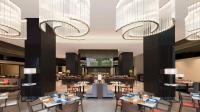 a restaurant with tables and chairs and chandeliers at Hilton Bengaluru Embassy Manyata Business Park in Bengaluru