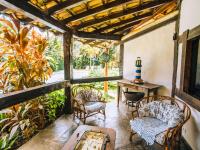 um alpendre com cadeiras e uma mesa em VELINN Pousada dos Marinheiros em Ilhabela