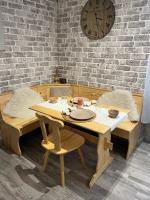 a wooden table with chairs and a clock on a brick wall at Petit appartement T2 30m2 in Aix-les-Bains