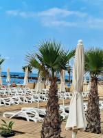 a beach with white chairs and palm trees and umbrellas at Bungalow de 3 chambres avec piscine partagee et terrasse a Vias a 1 km de la plage in Vias