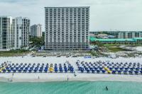 ein Strand mit blauen und weißen Sonnenschirmen und ein Gebäude in der Unterkunft Pelican Beach Resort by Colasan in Destin