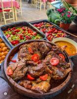 Una bandeja de comida con carne y verduras sobre una mesa. en Wood Mood Apartman Tiganjica, en Staji°evo