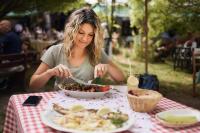 una mujer sentada en una mesa con un tazón de comida en Wood Mood Apartman Tiganjica, en Staji°evo