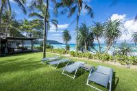 a row of lounge chairs on the grass near the beach at Katathani Phuket Beach Resort - SHA Extra Plus in Kata Beach