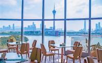 Un restaurante con mesas y sillas y vista a la ciudad. en YOHO Treasure Island Hotel, en Macau