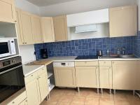 a kitchen with white cabinets and blue tiles on the wall at Maison de ville in Valençay