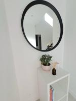 a round mirror on a white wall above a white table at Maison de vacances à Loctudy in Loctudy