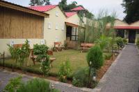 un jardín frente a una casa con un banco en Rann Meadows Ranthambhore, en Sawāi Mādhopur