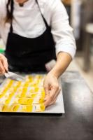 a woman in a kitchen preparing food on a counter at La Bastide Bourrelly - Mathias Dandine in Cabriès