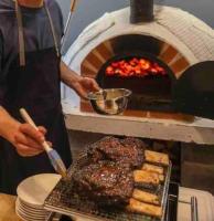a person cooking meat in a pizza oven at Lovely apartment by the sea. in Ķesterciems