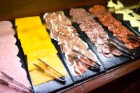 a display case with different types of meats and cheese at ALEGRIA Bodega Real in El Puerto de Santa María