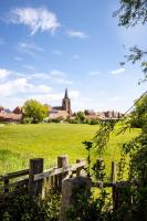 a fence in a field with a church in the background at Vakantieverblijf De Backstage in Heuvelland