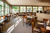 a dining room with tables and chairs and windows at Sheraton San Jose Silicon Valley in Milpitas