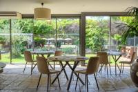 Un comedor con mesas y sillas y ventanas. en Villa Augusta, en Saint-Paul-Trois-Châteaux
