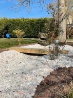 a garden with a bench in the middle of gravel at Bienvenue au Gite La So Sweet in Rully