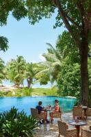 dwie osoby siedzące przy stolikach przy basenie w ośrodku wypoczynkowym w obiekcie Constance Lemuria w mieście Grand'Anse Praslin