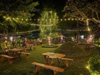 Un grupo de mesas de picnic en un parque con luces en Hotel Tharu Garden And Beer Bar, en Chitwan