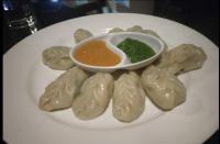 a plate of dumplings with a bowl of dipping sauce at Hotel Mirage Regency in Kathmandu